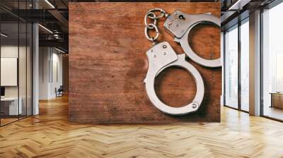 Handcuffs isolated and copy space on a wooden background. Wall mural