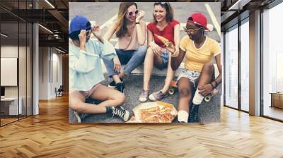 A diverse group of women sitting on the floor and eating pizza together Wall mural