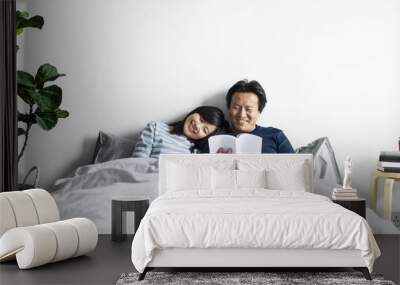 Asian couple relaxing on bed together Wall mural