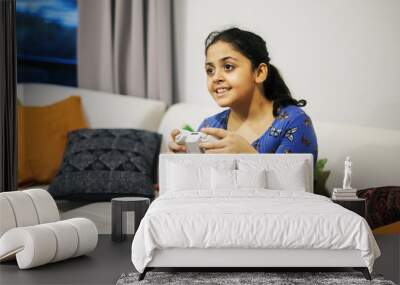 Brazilian girl playing game with joystick in living room Wall mural