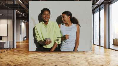 Cheerful friends looking at a phone Wall mural