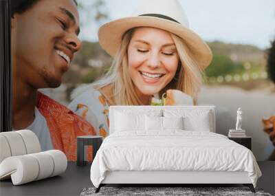 Couple dating and eating sandwiches at a beach picnic Wall mural