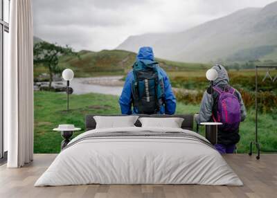 Couple trekking through the rain in the Highlands Wall mural