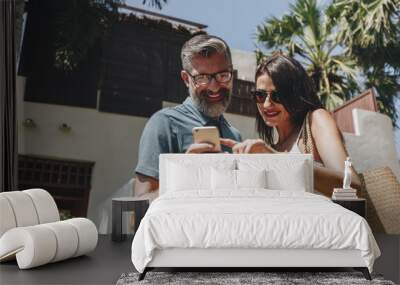 Couple using their phone while on vacation Wall mural