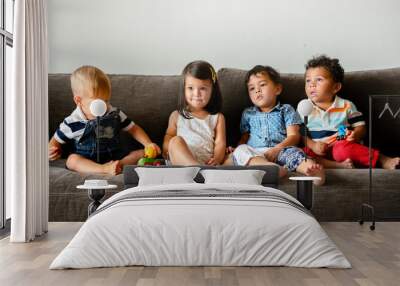 Diverse young kids sitting on the couch together Wall mural