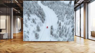 Drone view of a red car driving though a snowy forest in Lapland, Finland Wall mural