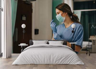 Female nurse with a mask putting on gloves Wall mural