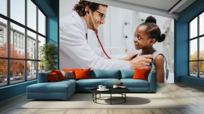 Friendly pediatrician checking a little girls heart Wall mural