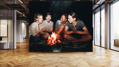 Group of friends sitting around a bonfire at a campsite Wall mural