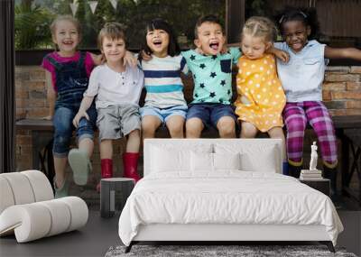 Group of kindergarten kids friends arm around sitting and smiling fun Wall mural