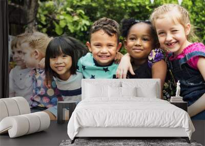 Group of kindergarten kids friends arm around sitting and smiling fun Wall mural