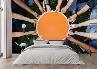 Group of people holding a round orange board Wall mural