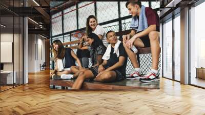 Group of young teenager friends sitting on a bench relaxing Wall mural