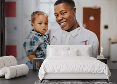 Happy pediatrician carrying a young boy Wall mural