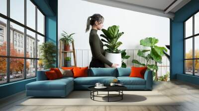 Happy woman carrying a houseplant Wall mural