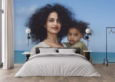 Indian mom piggyback baby on a beach photography portrait outdoors. Wall mural