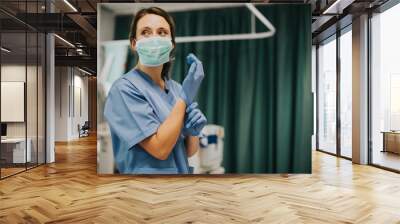 Nurse putting on gloves in hospital room Wall mural