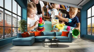 Nursery children playing with teacher in the classroom Wall mural