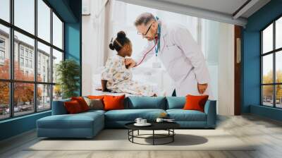 Physician listening to the heart beat of a little girl Wall mural