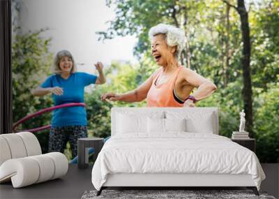 Senior woman exercising with a hula hoop Wall mural