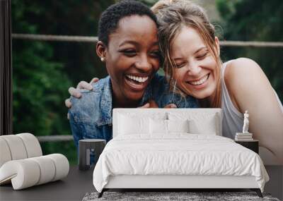 Two girl friends laughing and embracing each other Wall mural