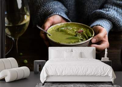 Woman holding a bowl of green pea soup Wall mural