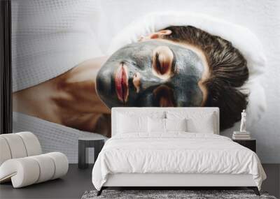 Woman relaxing with a charcoal facial mask Wall mural