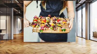 Woman serving vegan barbecue skewers on a wooden board Wall mural