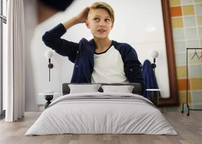 Young caucasian boy set hair with mirror in bathroom Wall mural