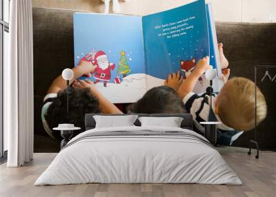 Young kids reading a Christmas story together Wall mural