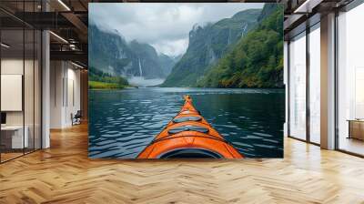 A kayak is in the middle of a lake, with mountains in the background Wall mural