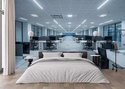 An empty modern office with white walls and light grey carpeted flooring, featuring rows of desks arranged side by side. The space is well lit from the ceiling lights above each desk. Wall mural