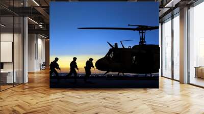 Special force unit running toward to boards military transport helicopter at sunset Wall mural