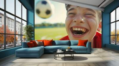 A close-up of a young teen's face, joyfully playing soccer, with the field's background soft and a clear sky above for text.  Wall mural