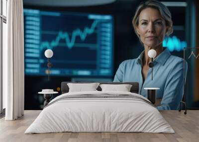 A confident middle-aged female financial advisor stands in a modern office with financial charts in the background, ready to guide clients towards success. Wall mural