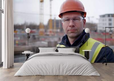 A portrait of a middle-aged European man in safety gear at a construction site, conveying professionalism and determination in an urban environment. Wall mural