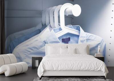 Blue and white classic man's shirts on hangers in a wardrobe Wall mural