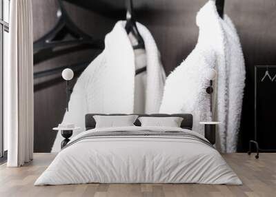 Two white cozy cotton bathrobes, dressing gowns hanging in a wardrobe at a hotel room Wall mural