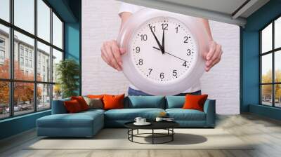 Woman holding clock showing five minutes to twelve, deadline and urgent work concept Wall mural