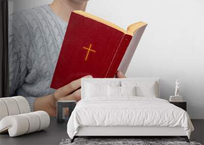 Young praying christian woman's hands holding holy bible with a cross on a cover Wall mural