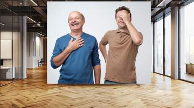 Two friends in casual colorful wear standing and laughing together. Best friends enjoying life. Two men having fun. Wall mural