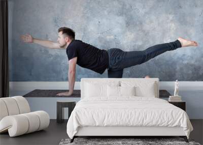 Young caucasian men practices yoga asana chakravakasana Wall mural