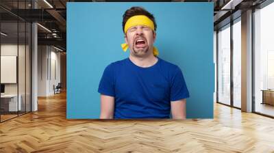 Young caucasian sport man with yellow rubber band whining and crying Wall mural