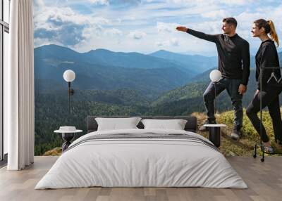 The couple gesturing on the mountain with a picturesque cloudscape Wall mural