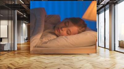 The cute girl sleeping on the bed. Evening night time Wall mural