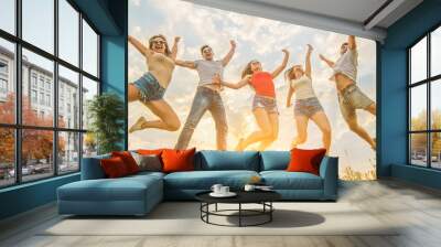 The five friends jumping on the grass on the sunny background Wall mural