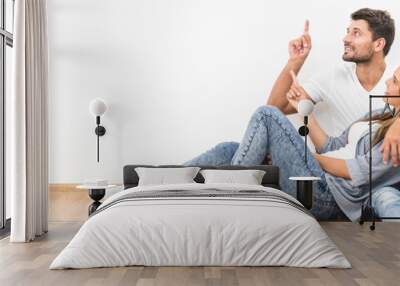 The happy couple sit and gesture on the background of the white wall Wall mural