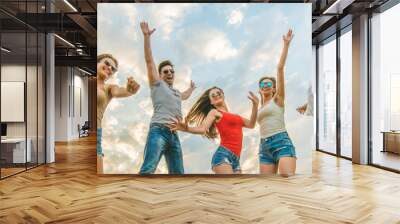 The happy friends jumping on the background of the clouds Wall mural