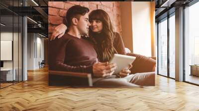 The happy man and a woman sitting with a tablet in the restaurant Wall mural