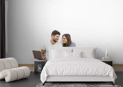 The happy man and woman with a laptop sit near the empty wall Wall mural